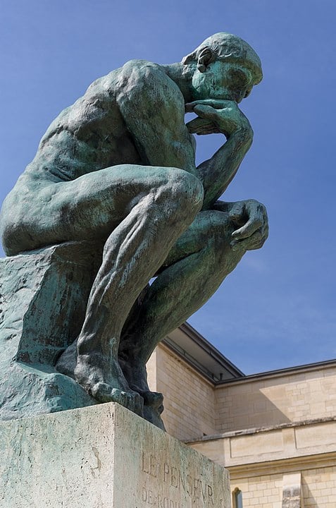 Photograph of Auguste Rodin's sculpture, 'The Thinker,' which is made of bronze.