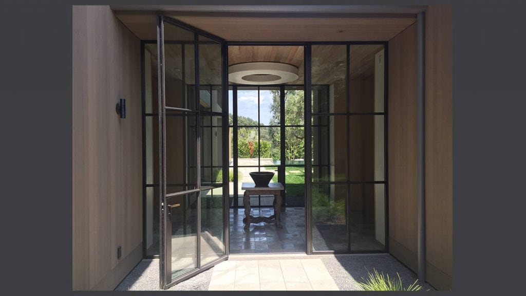 Image of a steel door opening up into a modern home